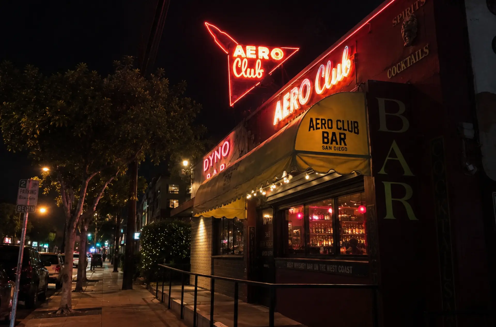 Aero Club Bar exterior at night in San Diego with glowing red neon sign and yellow awning